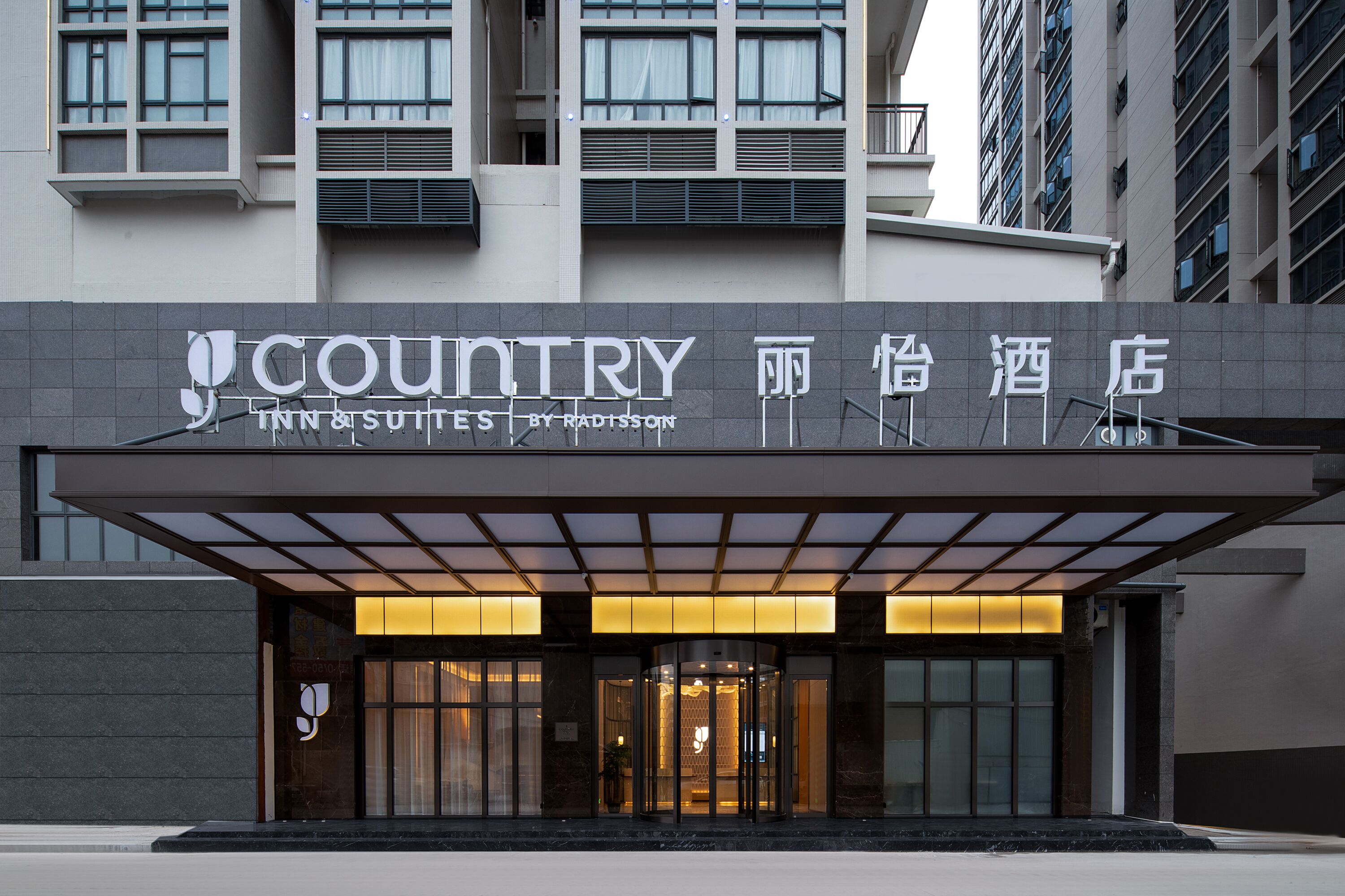 A hotel entrance with a modern design, featuring a sign for 'Country Inn & Suites by Radisson' and Chinese characters.
