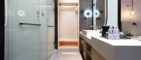 A modern bathroom with a glass shower enclosure, a vanity with a mirror, and a countertop with toiletries.