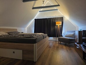 Une chambre à coucher avec un lit, une chaise, une lampe et un téléviseur.