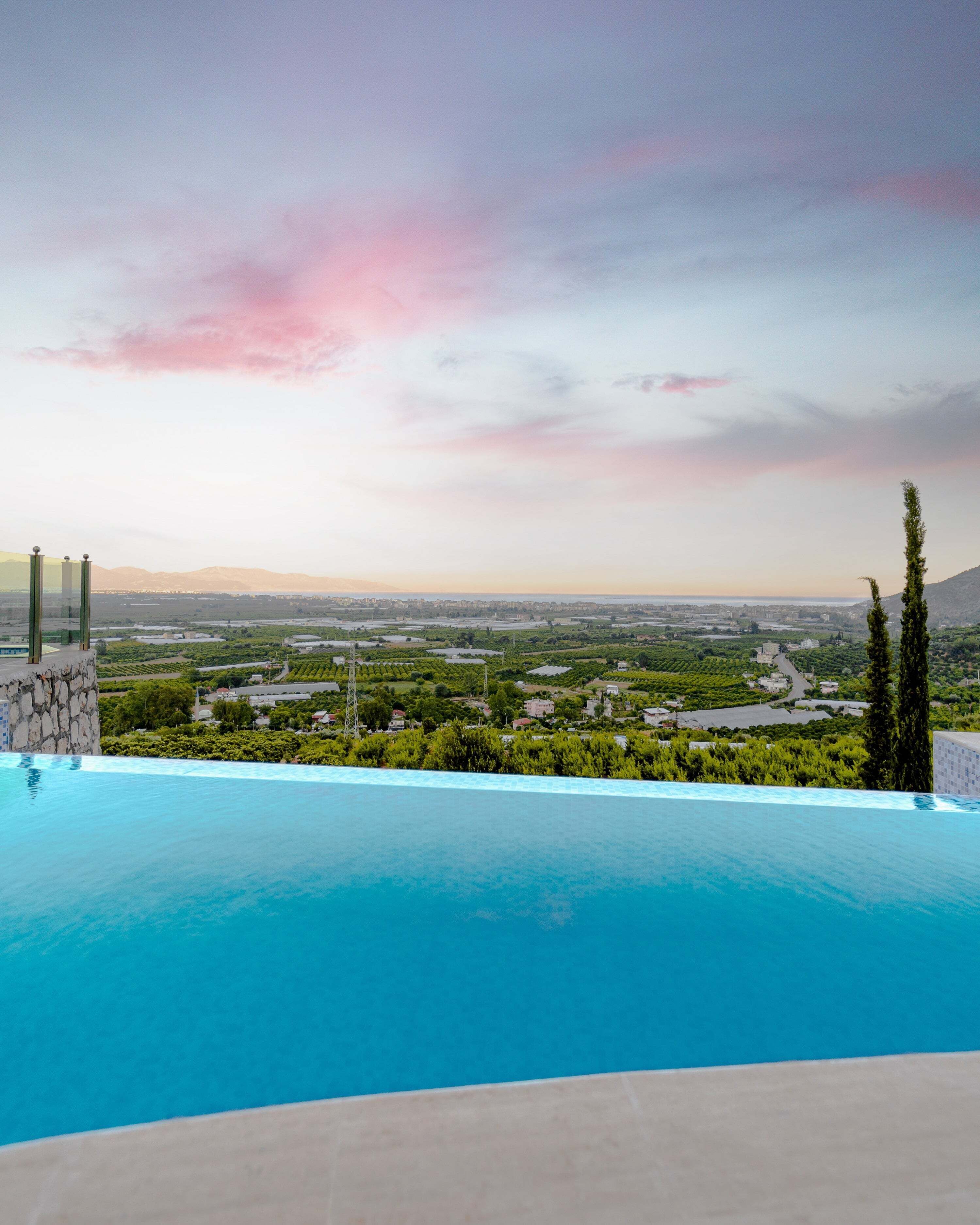Una piscina infinita con vistas a un paisaje urbano y montañas a lo lejos.