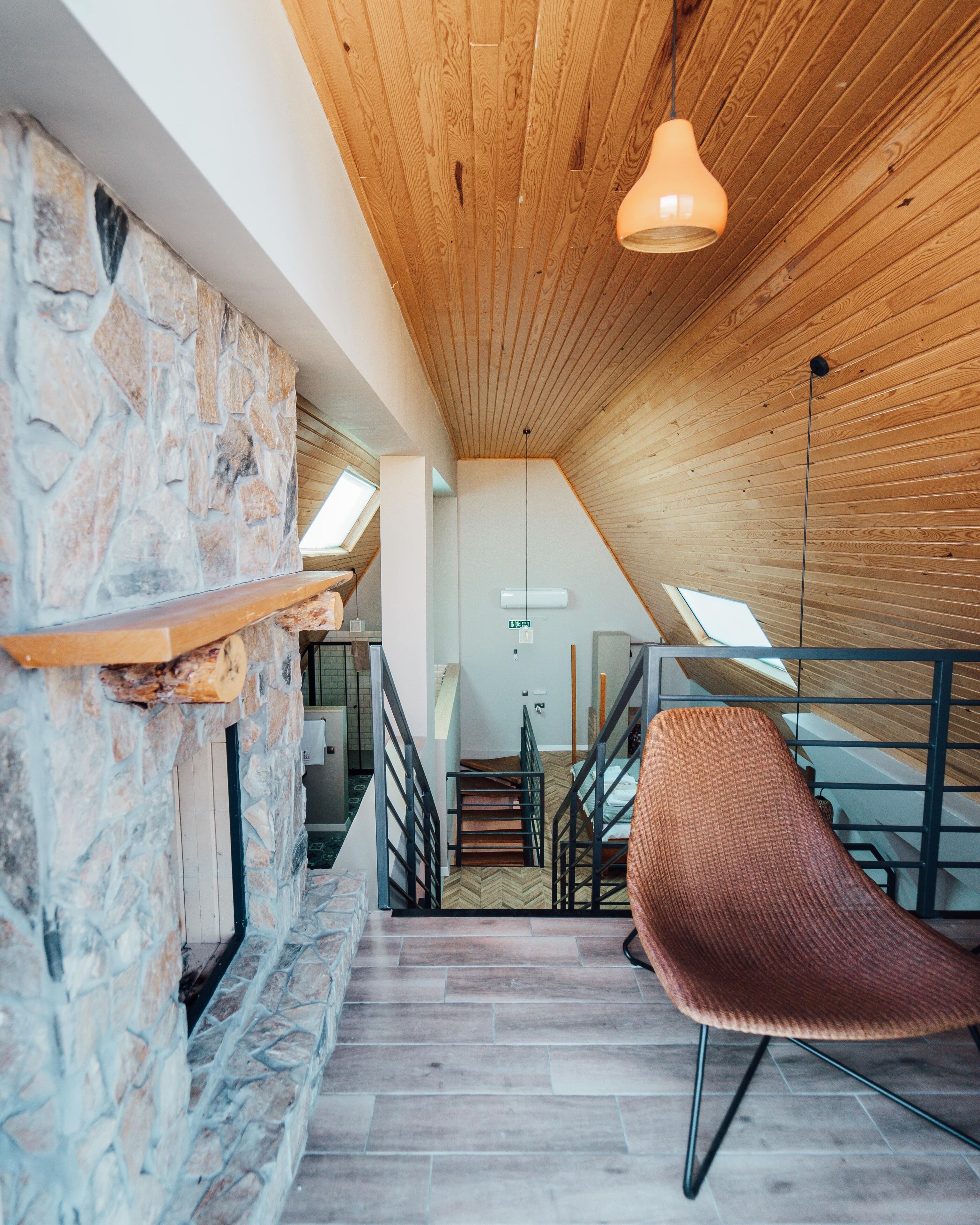 A modern interior with a stone wall, wooden ceiling, and a staircase leading to an upper level.