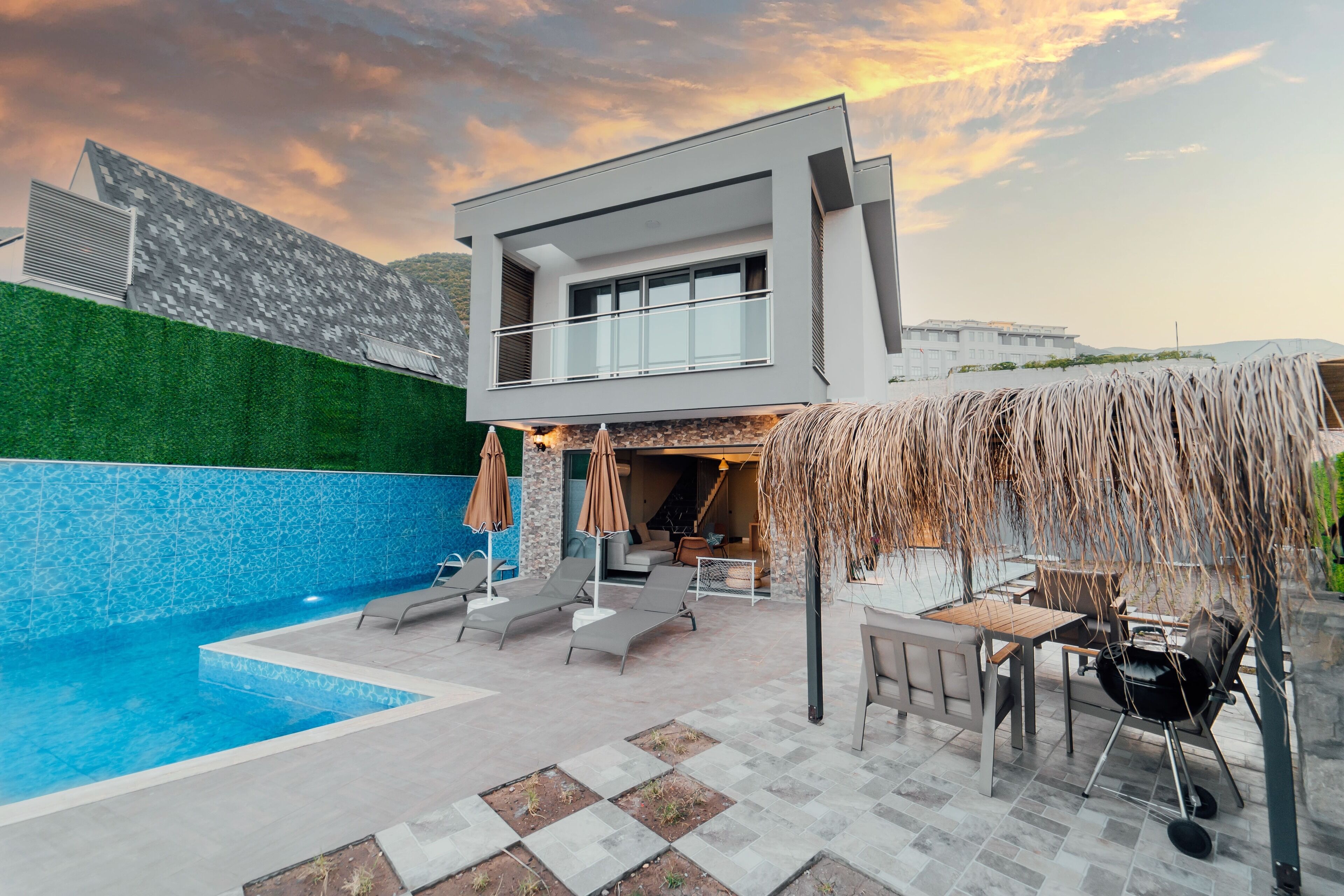 A modern house with a swimming pool, outdoor seating, and a barbecue area.