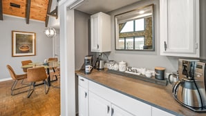 A modern kitchen with white cabinets, a coffee maker, and a stone backsplash.