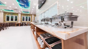 A buffet setup with multiple serving stations, a seating area with tables and chairs, and a ceiling with a cloud-themed light display. - Thao Nho Hotel Phu Quoc - by Bay Luxury (Phu Quoc)