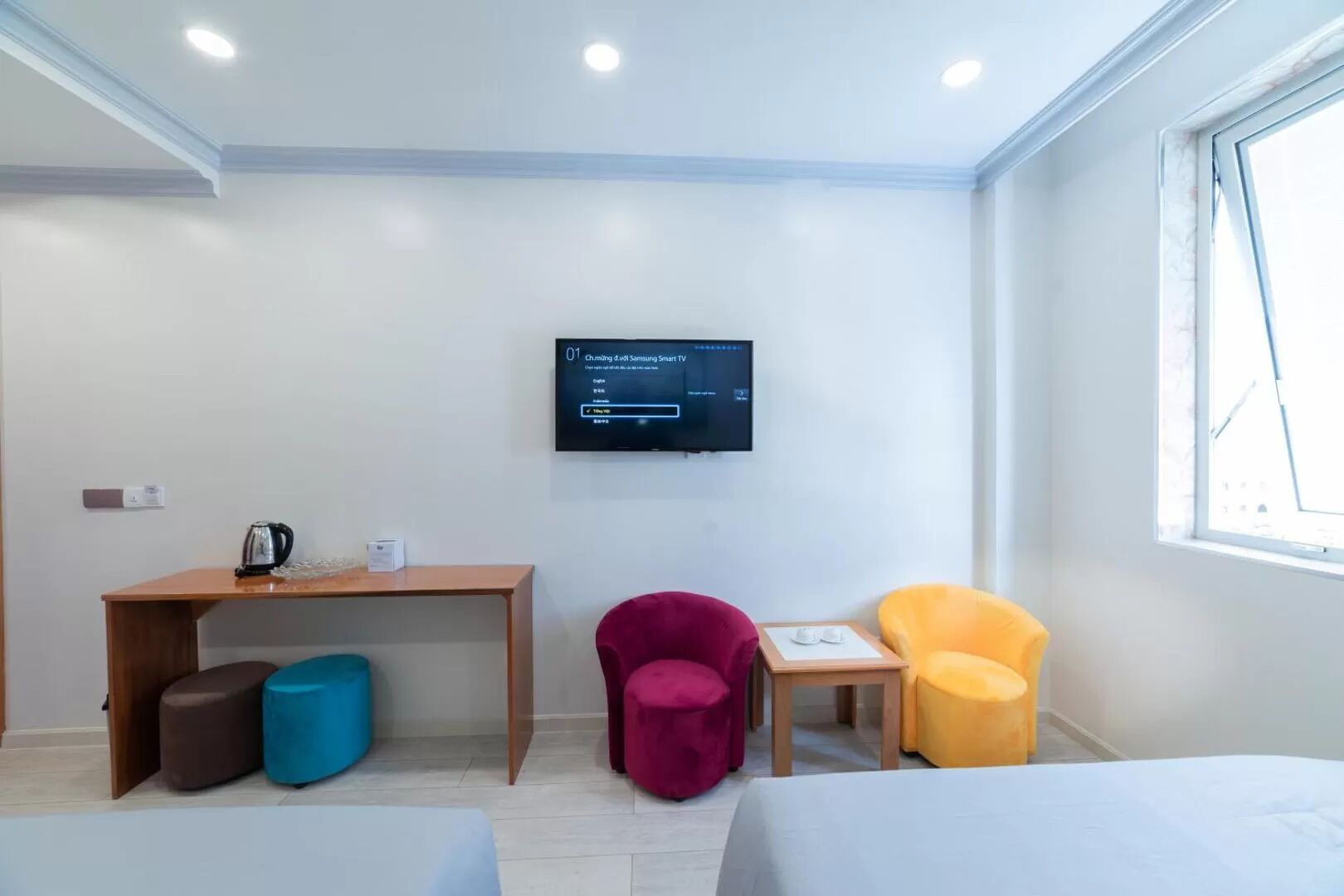 Ein Hotelzimmer mit Bett, Schreibtisch, Fernseher und zwei Stühlen.