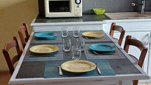 A dining area with a table set for four, including plates, cutlery, and glasses. - Gite de Mon Clocher Appartement 3ième Étage Avec Balcon Proche du Mercantour (Roquebilliere)