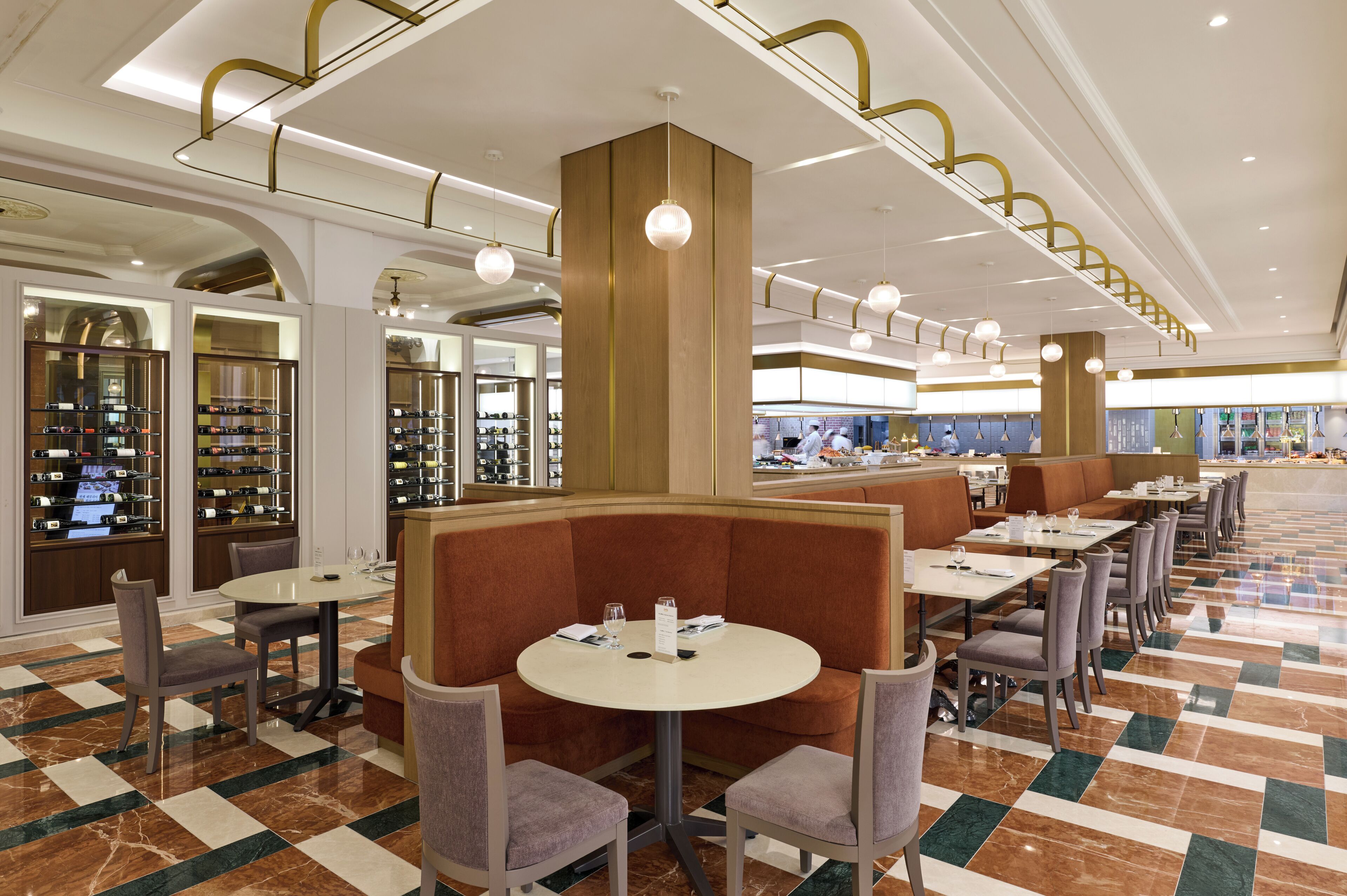 A modern hotel lobby with a central seating area, a wine cellar, and a dining section.