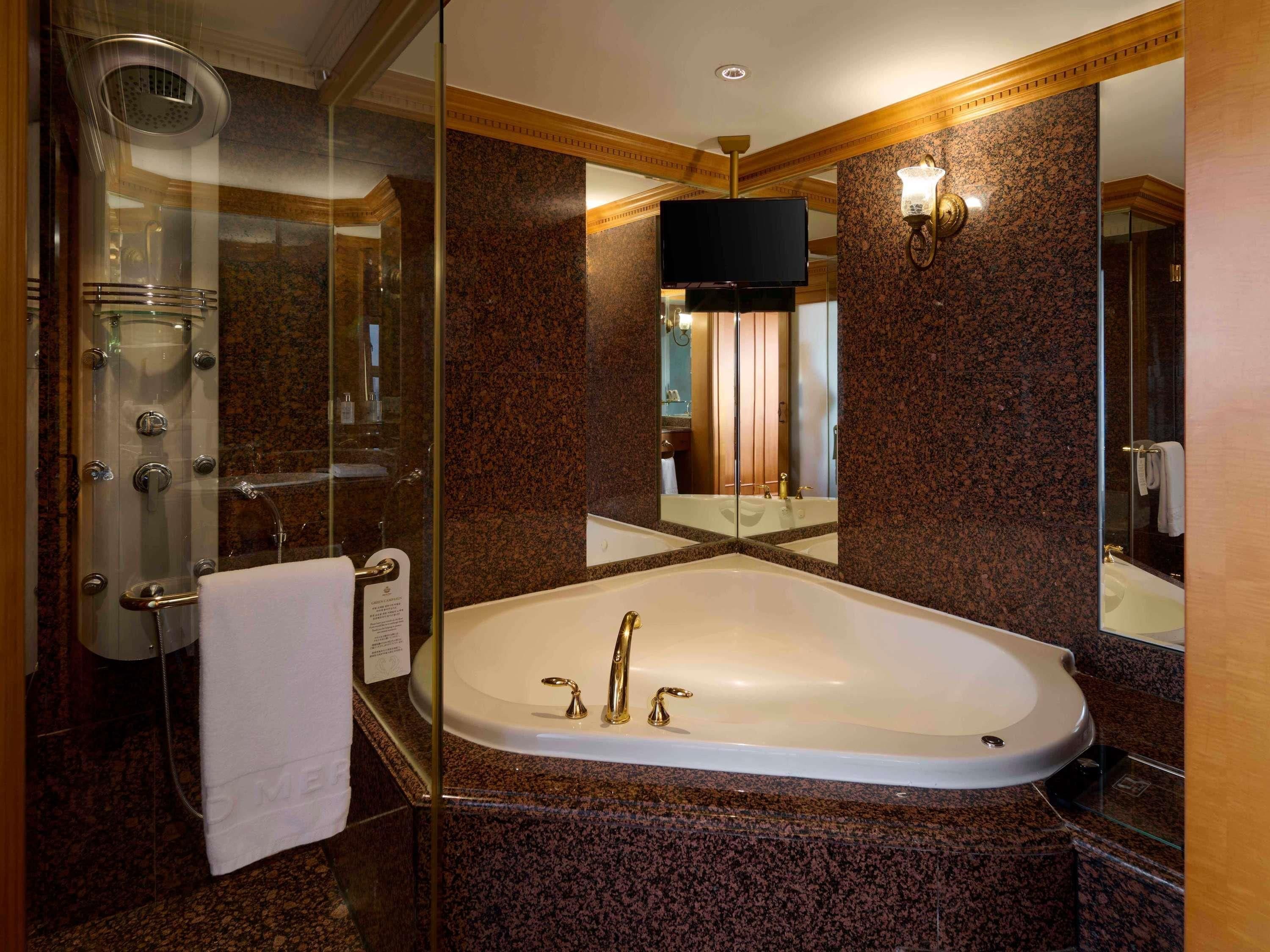 Un baño moderno con ducha de vidrio, una bañera independiente y un espejo grande que refleja el espacio.
