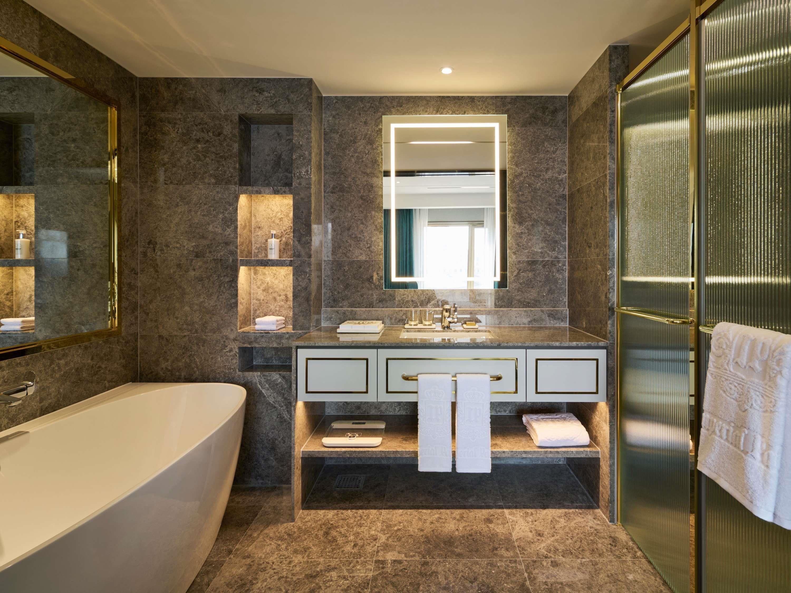 Un baño moderno con una bañera independiente, un espejo grande y una zona de ducha con mampara de cristal.
