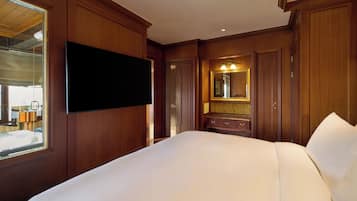 A hotel room with a large bed, wooden paneling, a flat-screen TV, a mirror, and a dresser.