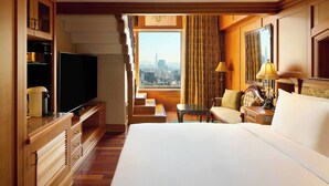 Habitación de hotel con una cama grande, televisión, escritorio, silla y vistas a la ciudad.