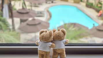 Dos ositos de peluche en un alféizar con vistas a una piscina.