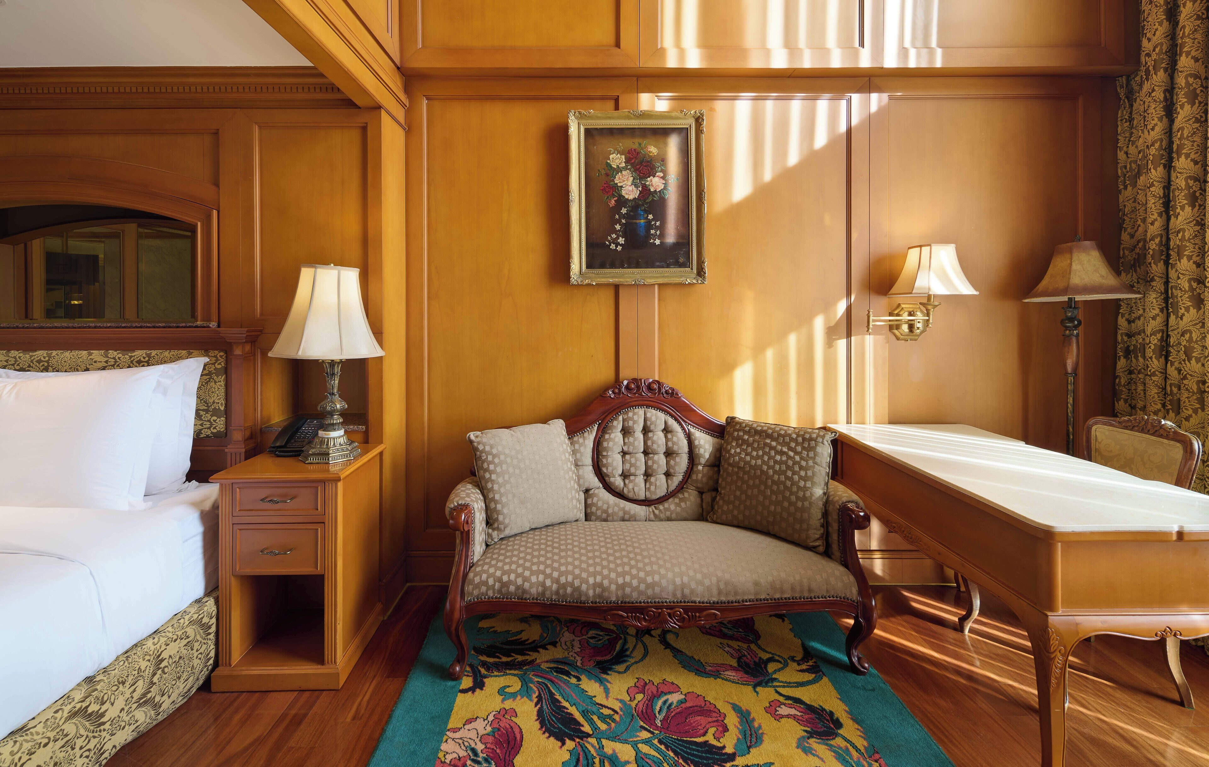 Una habitación de hotel con cama, sofá, escritorio y una obra de arte floral enmarcada en la pared.