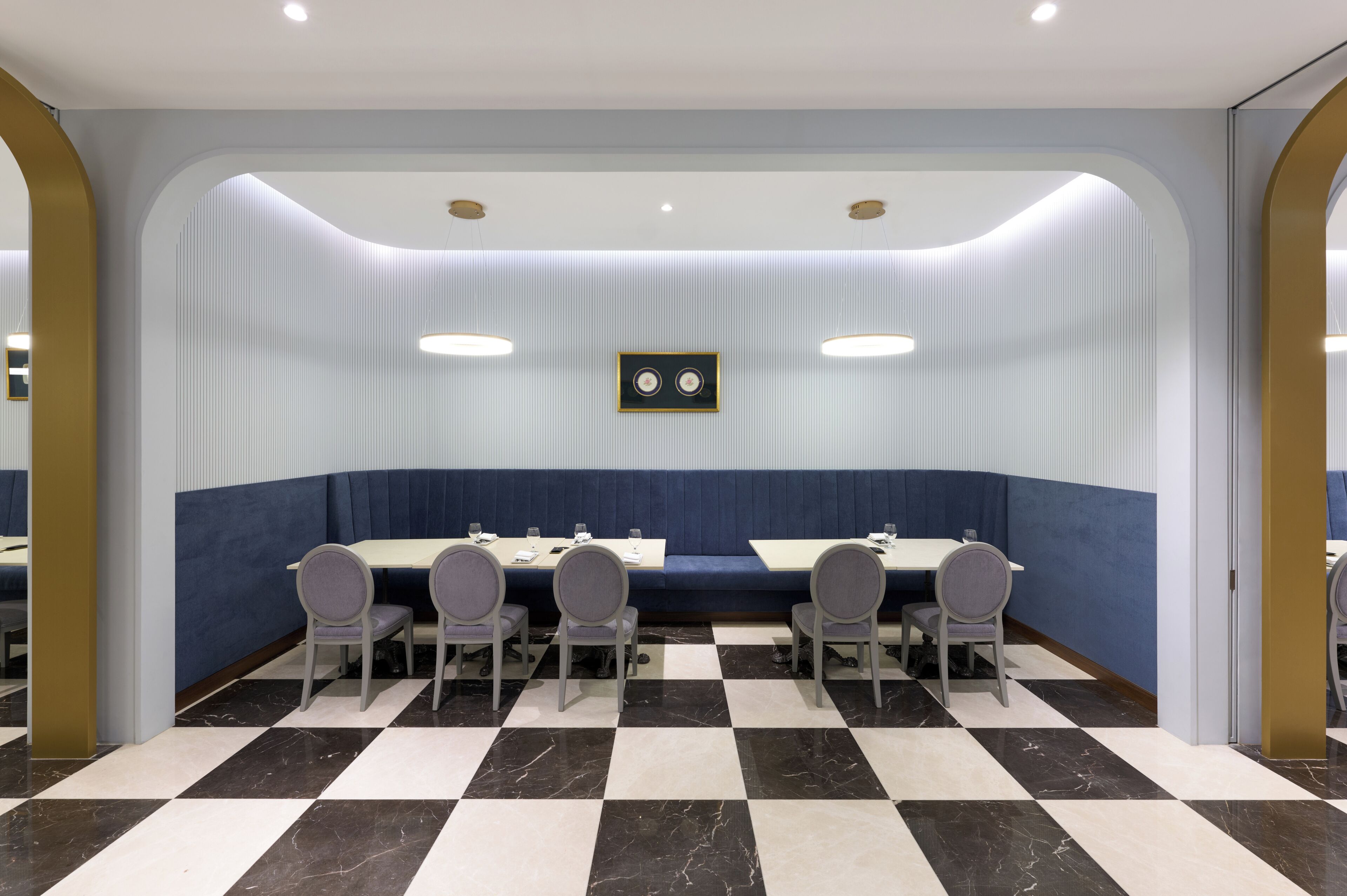 A conference room with a checkered floor, a blue cushioned bench, and a framed picture on the wall.