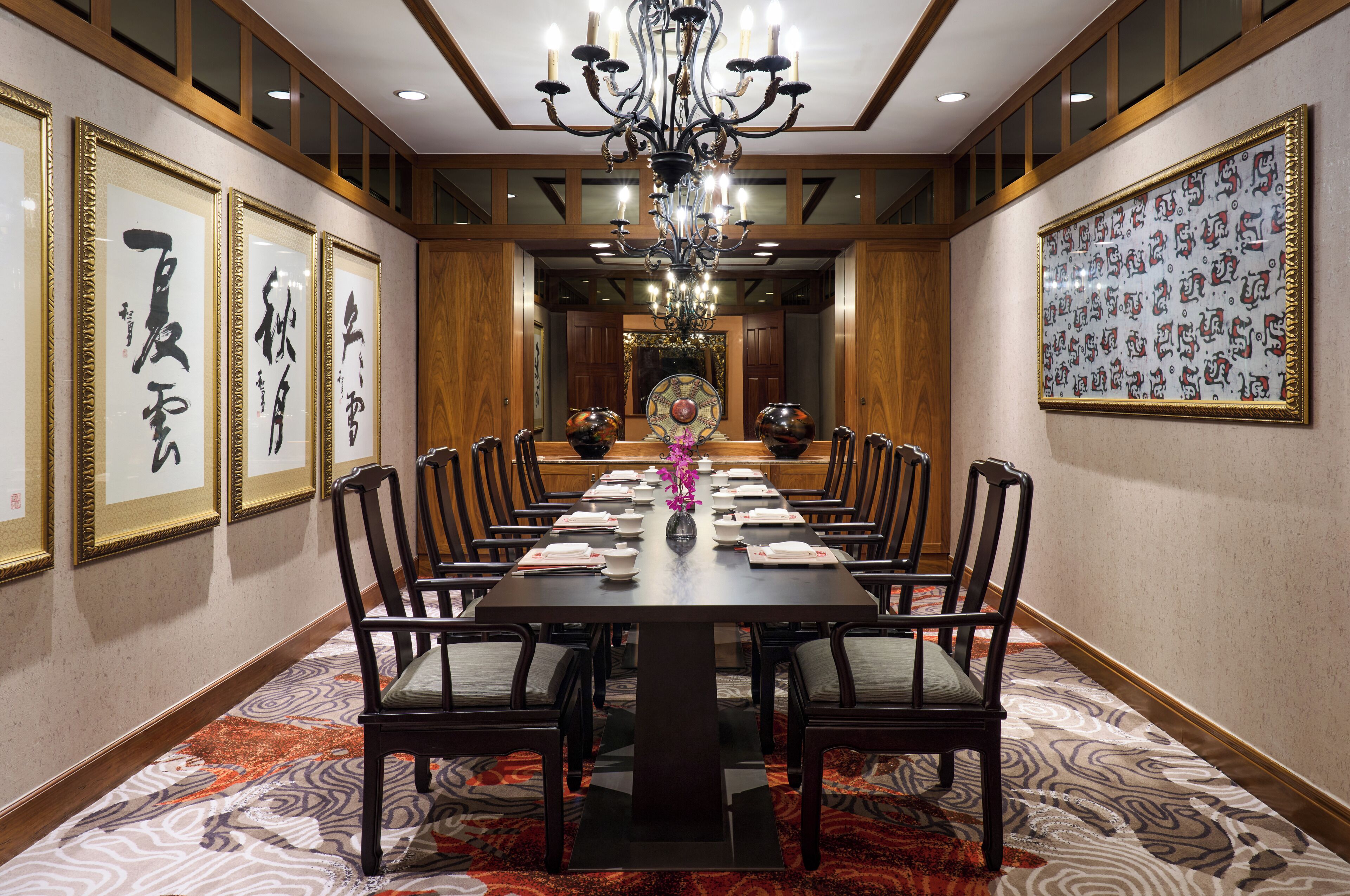 A conference room with a long table, chairs, and framed calligraphy on the walls.