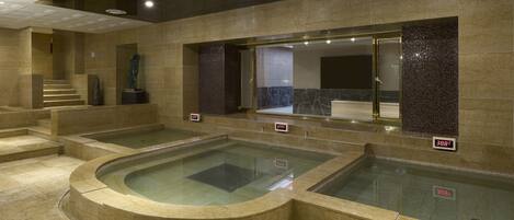 Un área de spa con varios jacuzzis y una escalera que sube a un nivel superior.