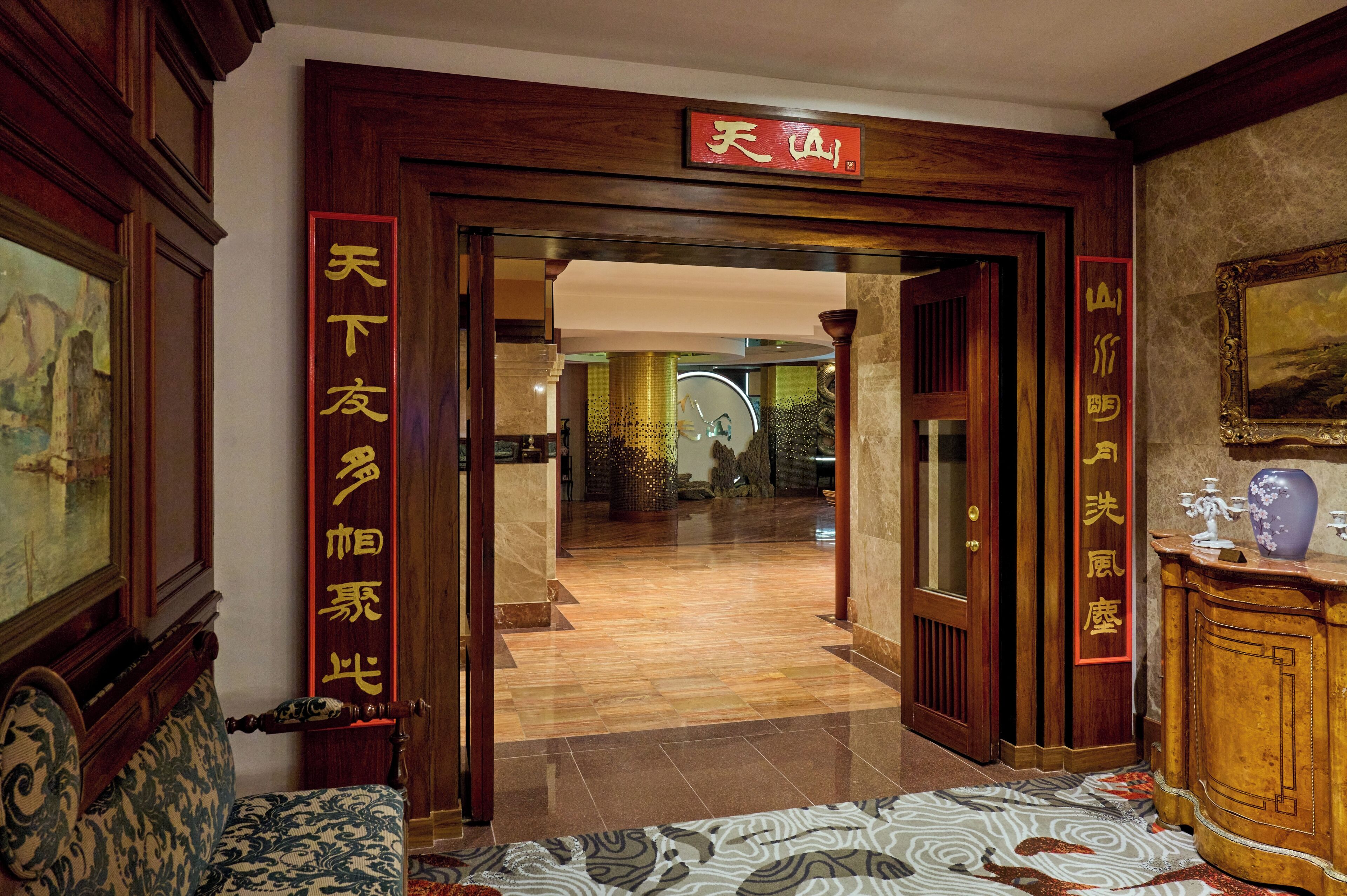 Un hall d’hôtel à la décoration traditionnelle, avec notamment des portes en bois et une enseigne ornée de caractères chinois.