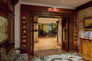 Un hall de hotel con decoración tradicional, que incluye puertas de madera y un letrero con caracteres chinos.