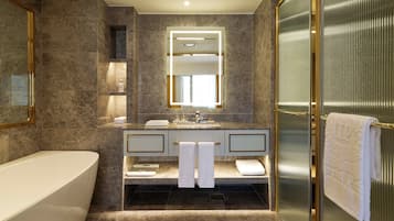 Un baño moderno con una bañera independiente, un espejo grande y un box de ducha de cristal.