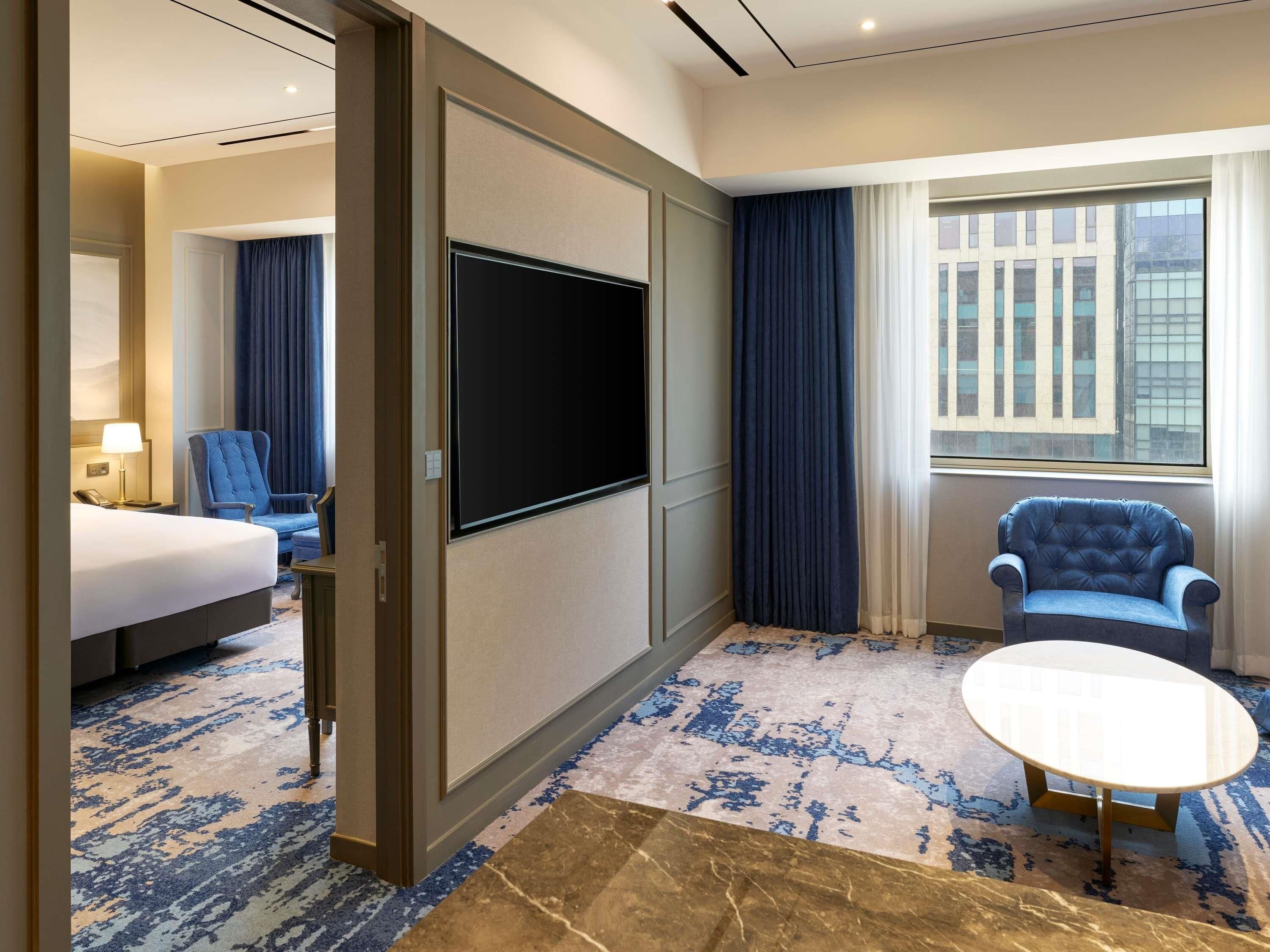 A hotel room with a bed, a desk, a chair, a television, and a window with curtains.