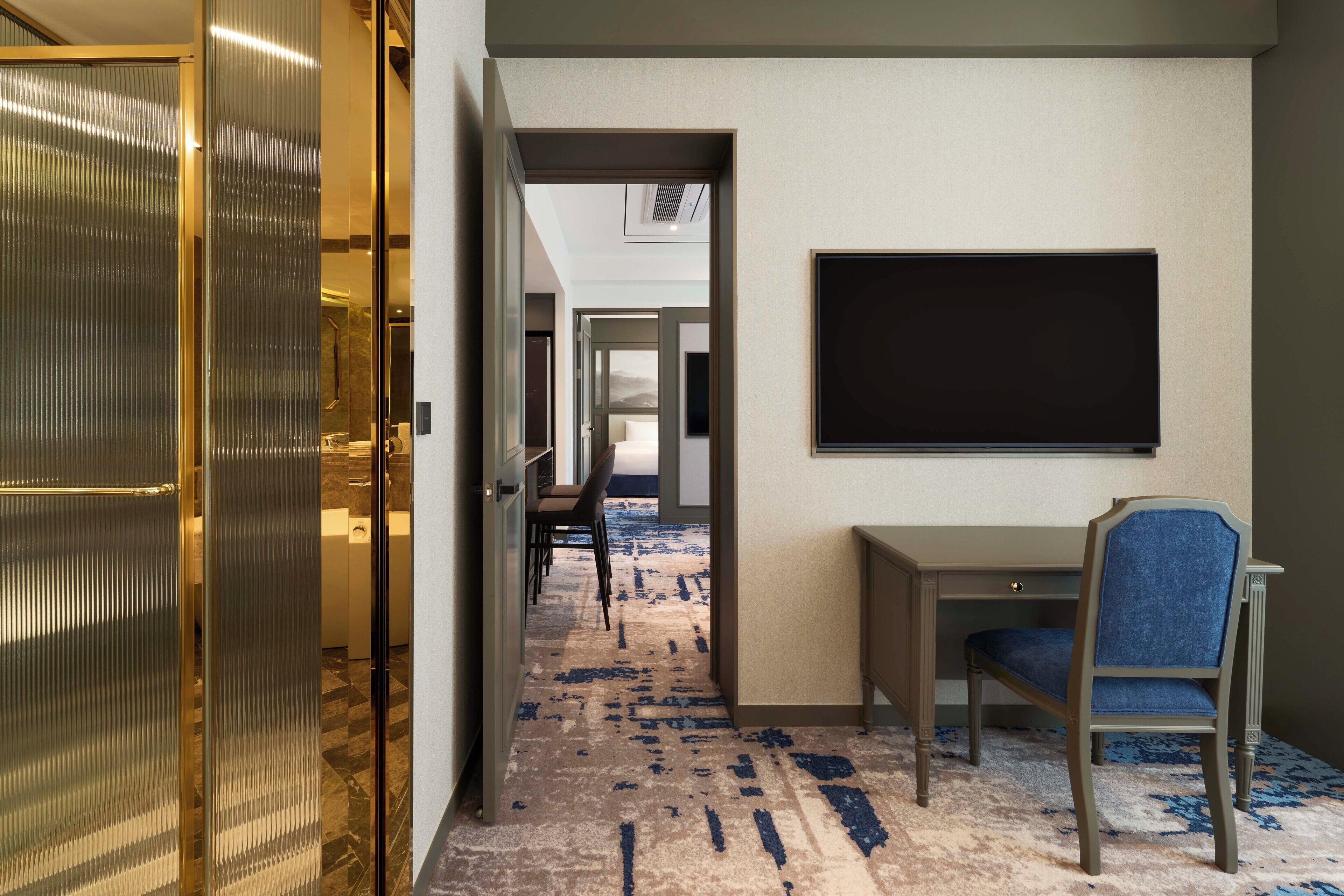 A hotel corridor with a desk and chair, a large blackboard, and a patterned carpet.