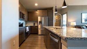 Eine moderne Küche mit Granit Arbeitsplatten, Edelstahlgeräten und Holzschränken.