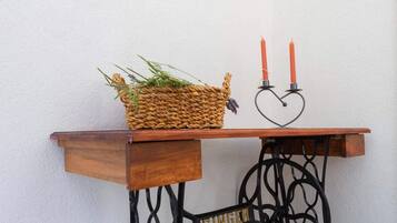 Una mesa de madera con una cesta trenzada y dos velas rojas sobre soportes con forma de corazón.