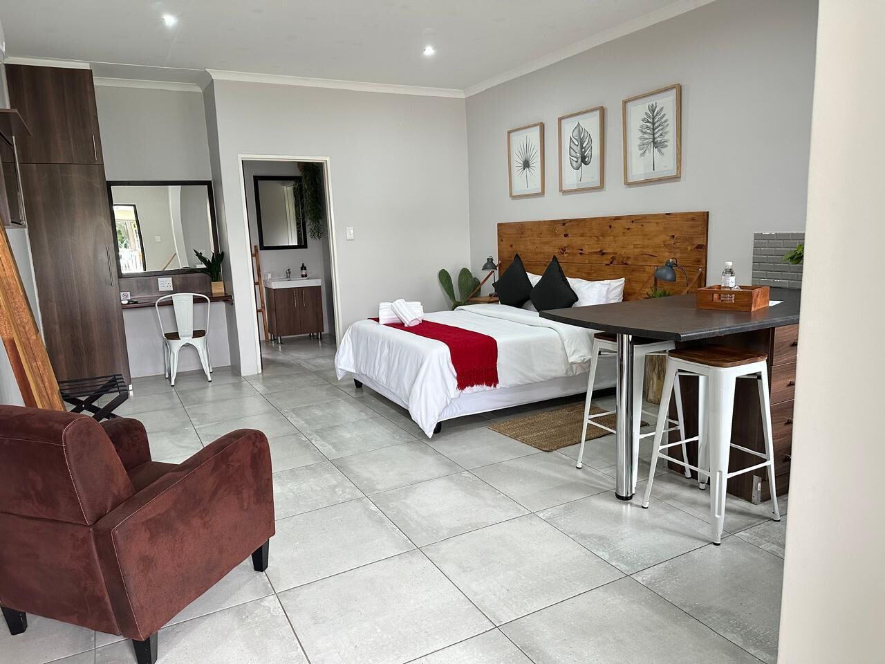 A modern hotel room with a bed, a desk, and a chair.