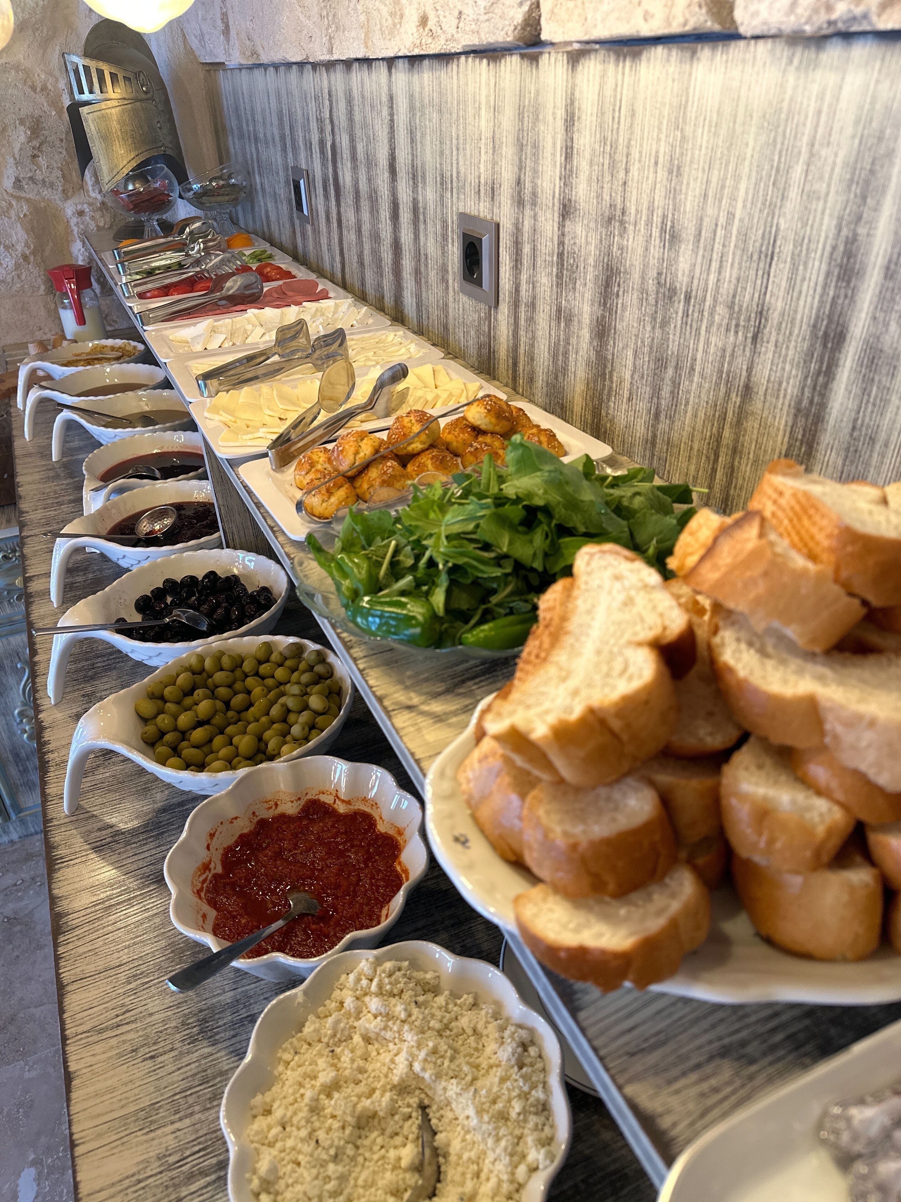 A buffet with various food items including olives, bread, and salads.