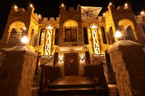 A historic building with a central entrance, arched windows, and illuminated signage.