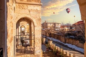 A stone building with an arched doorway, a view of a snow-covered street, and hot air balloons in the sky.