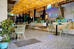 An outdoor seating area with tables and chairs, a sign reading 'ROVA', and potted plants. - StayBird Divine Suites Business Hotel (Pune)