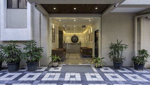 A modern entrance with a checkered floor, potted plants, and a central seating area. - StayBird Divine Suites Business Hotel (Pune)