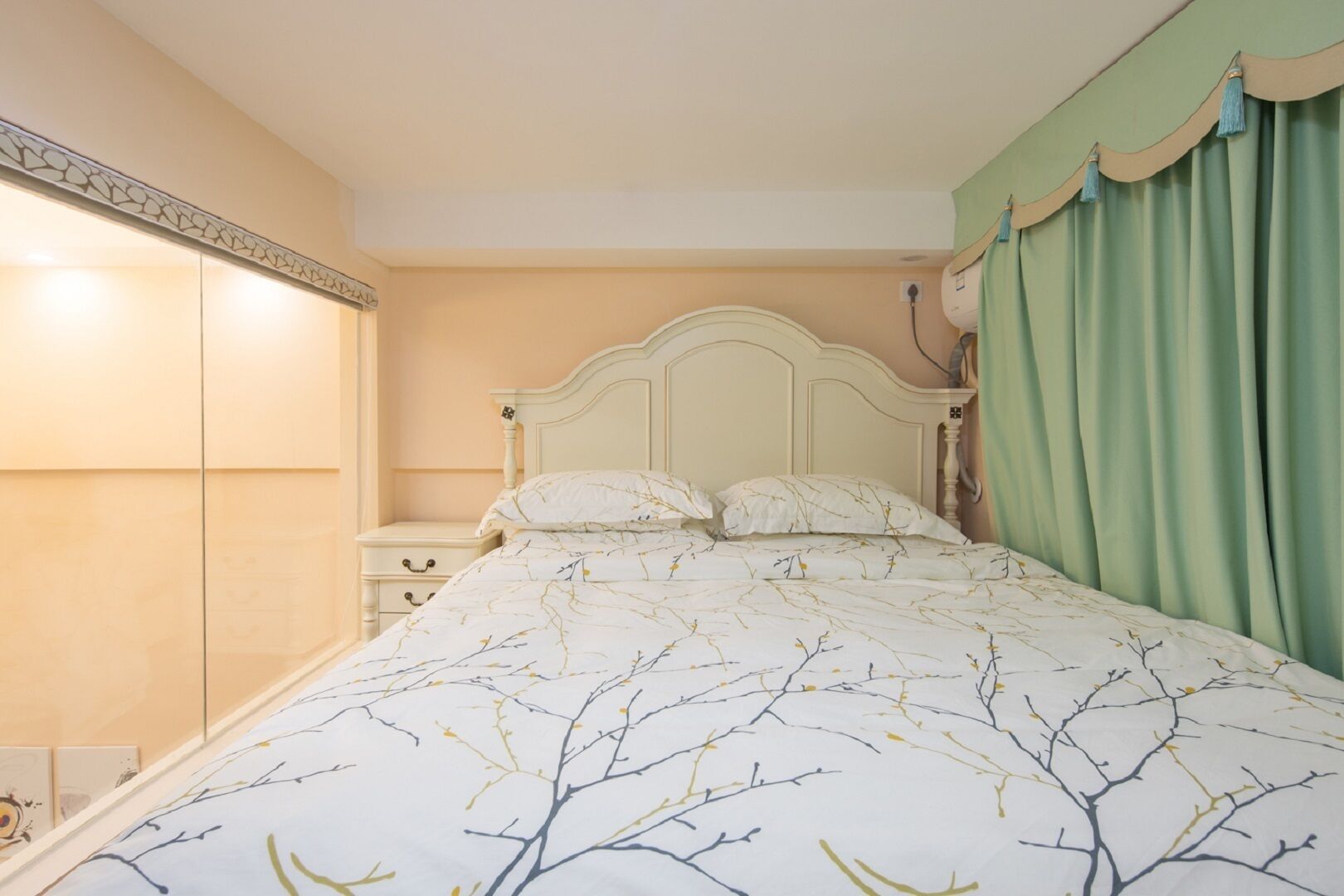 A bedroom with a bed, nightstands, a wardrobe, and a green curtain.