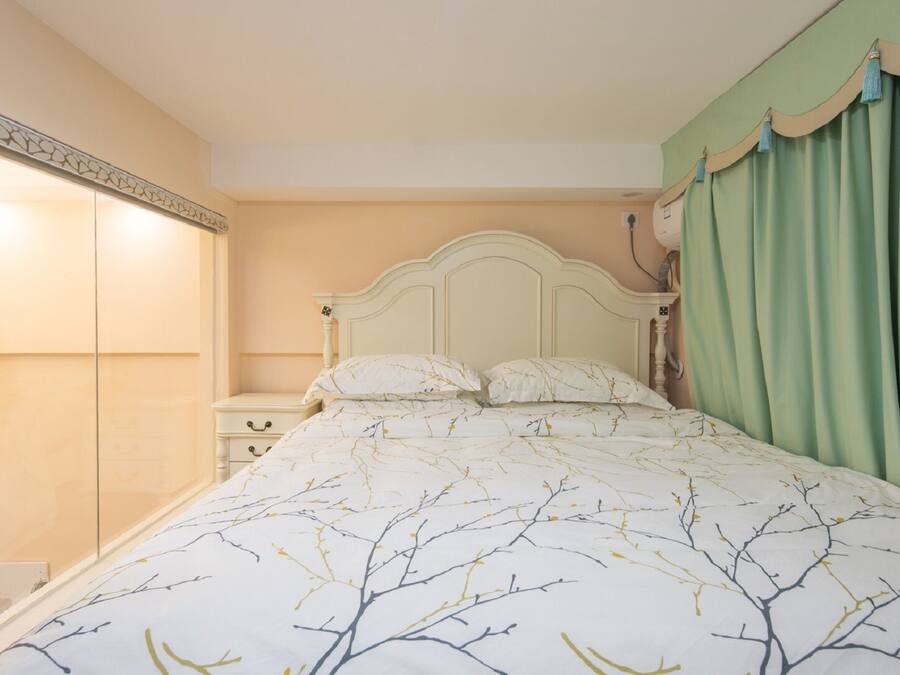 A bedroom with a bed, nightstands, a wardrobe, and a green curtain.