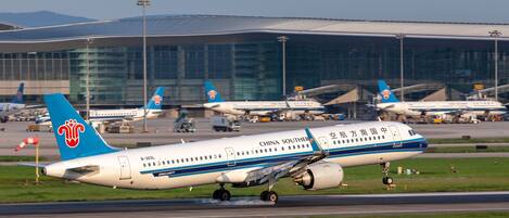 Ein Flughafen mit mehreren Flugzeugen, darunter eine China Southern Airbus A320, die landet.