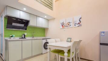 A compact kitchen with a dining area, a washing machine, and a refrigerator.