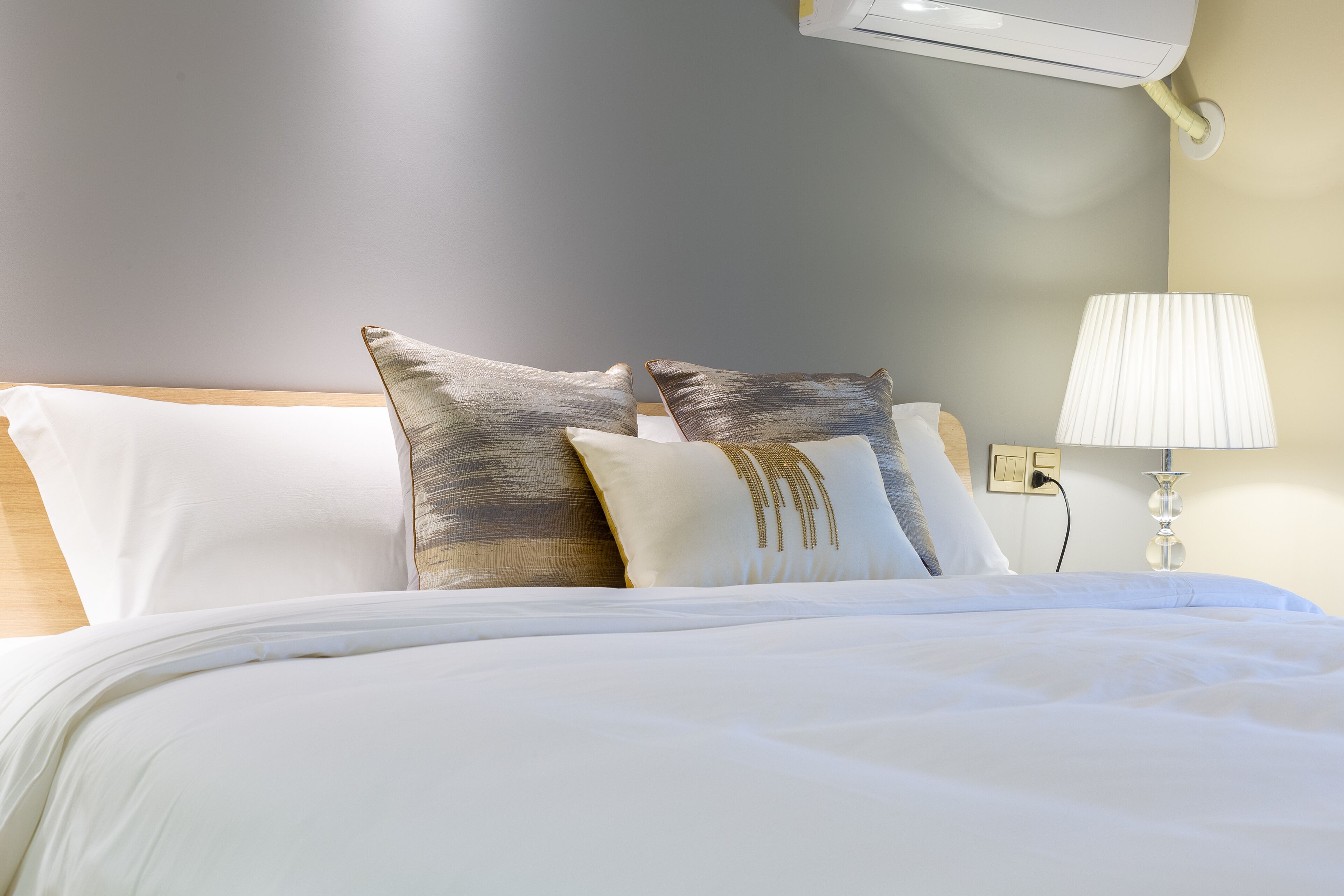 A neatly made bed with white bedding and two decorative pillows.
