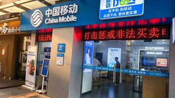 A storefront of China Mobile with a digital signboard, a Vivo advertisement, and a visible entrance.
