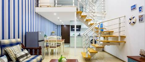 A modern living room with a sofa, coffee table, and a staircase with wooden steps and white railings.