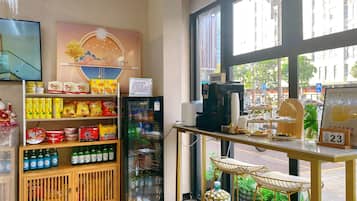 A coffee shop interior with a coffee machine, shelves of snacks, and a calendar displaying the date.