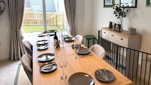 A dining area with a wooden table set for six, a hanging pendant light, and a view of the backyard through a window. - Insch House -  Retreat Group (Kingussie (nr Aviemore))