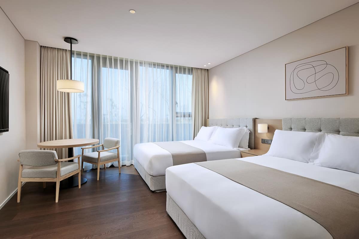 A hotel room with two beds, a round table, and chairs.