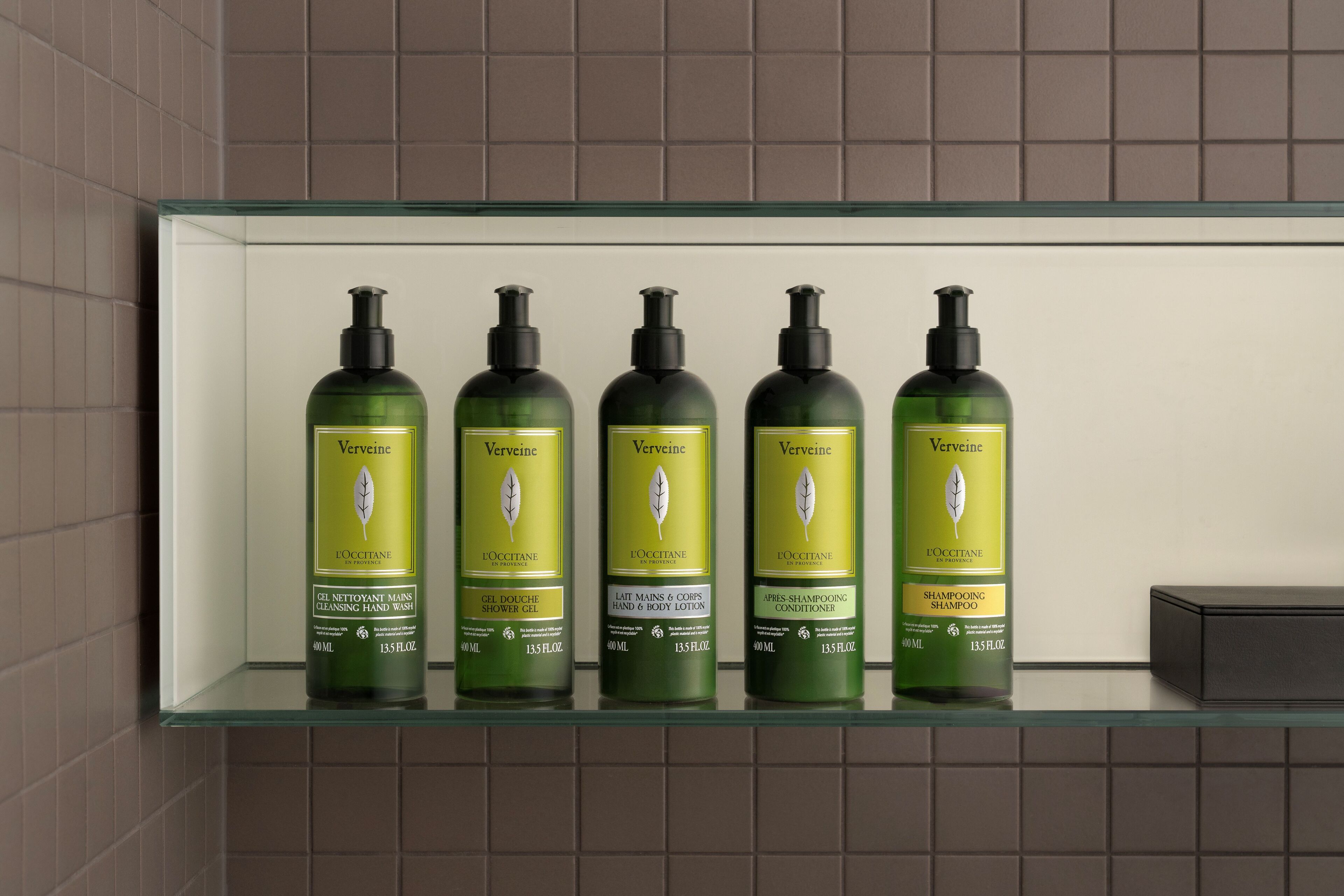Een badkamerplank met vijf flesjes Verveine toiletartikelen.