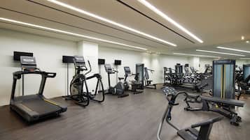 A modern gym with various cardio machines, weightlifting equipment, and a large mirror.