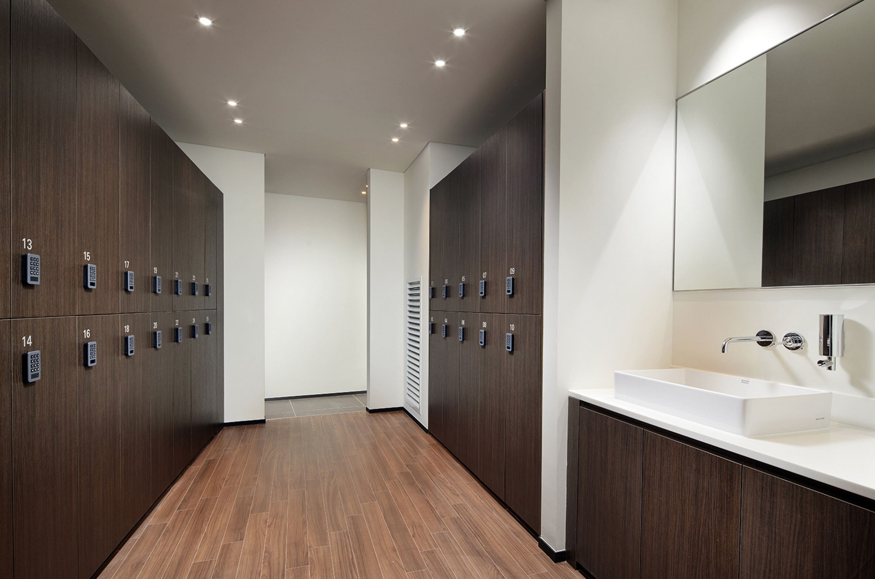 Ein modernes Hotelbad mit Holzschränken, einem weißen Waschbecken und einem großen Spiegel.
