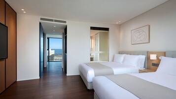 Habitación de hotel con dos camas, televisor y vista a la ciudad.