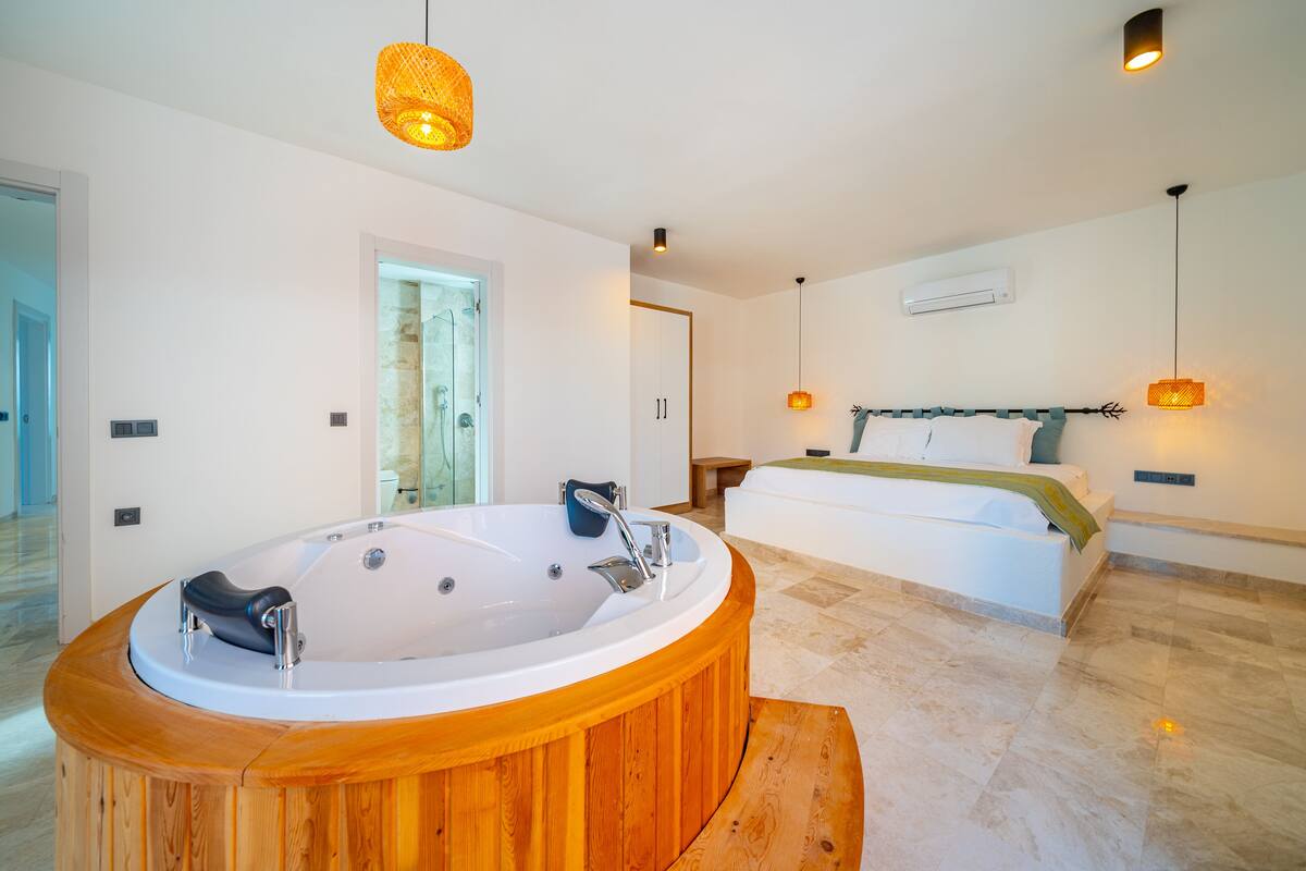 A modern bathroom with a wooden bathtub, a large mirror, and a shower area.