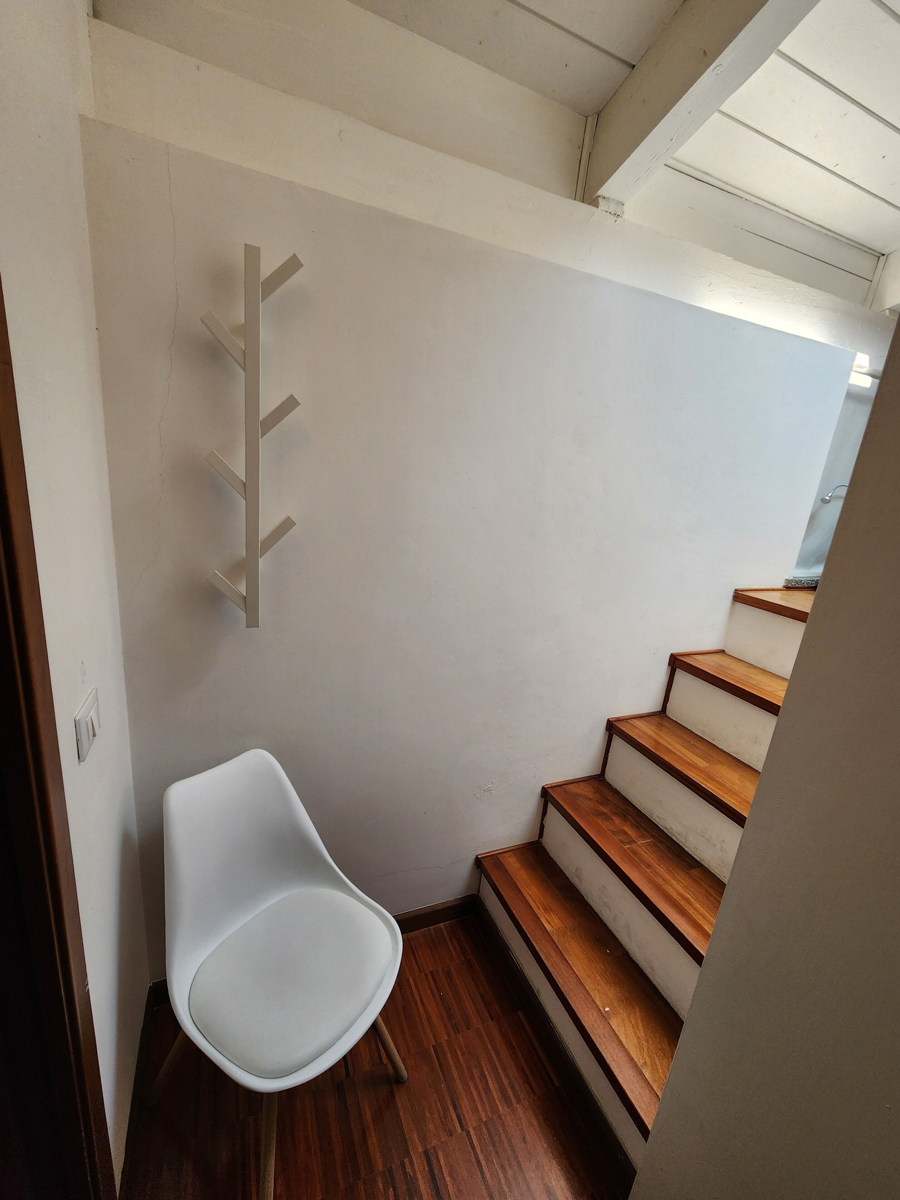 Eine Treppe mit Holzboden und ein weißer Stuhl in einem Flur.
