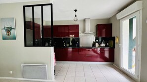 Una cocina moderna con armarios rojos, encimera negra y ventana que deja entrar luz natural.